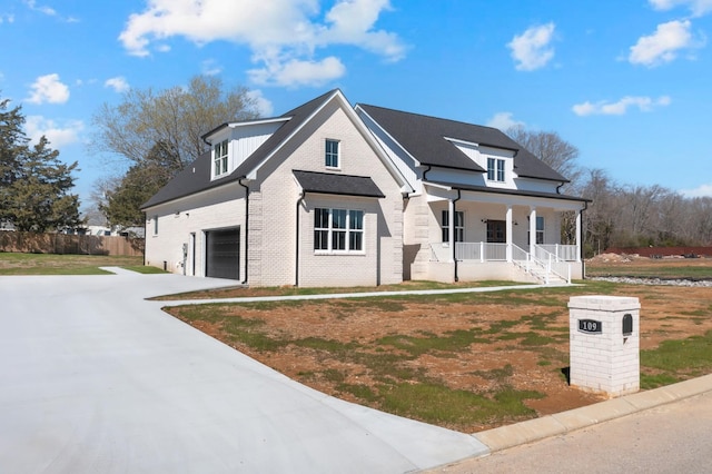 modern farmhouse featuring fence, a garage, brick siding, driveway, and a porch