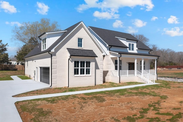 view of front of house featuring driveway, covered porch, an attached garage, and brick siding