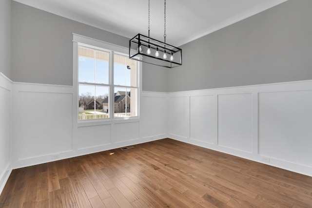 unfurnished dining area featuring visible vents, a wealth of natural light, wood finished floors, and a chandelier