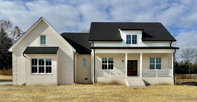 view of front of home with brick siding, a porch, and roof with shingles