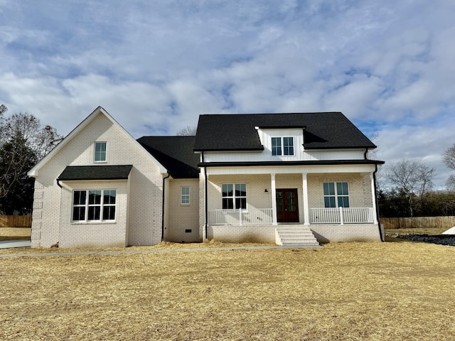 view of front of home with a shingled roof, a porch, and brick siding
