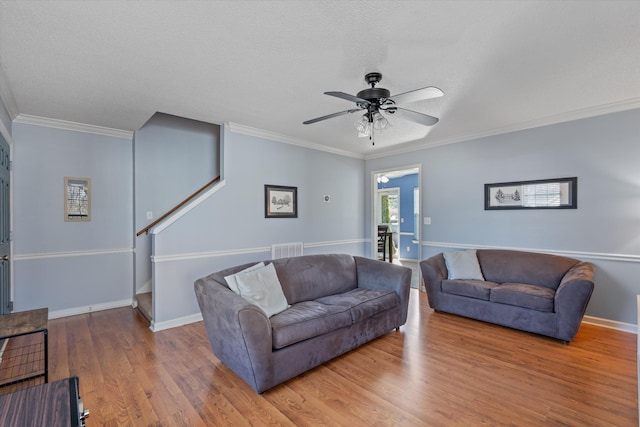 living room featuring crown molding, a textured ceiling, baseboards, and wood finished floors