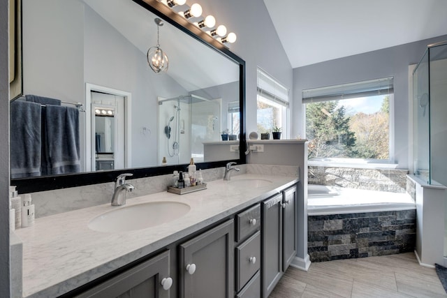 bathroom with vaulted ceiling, double vanity, a sink, and a shower stall