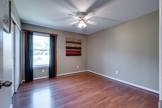 empty room featuring ceiling fan, baseboards, and wood finished floors