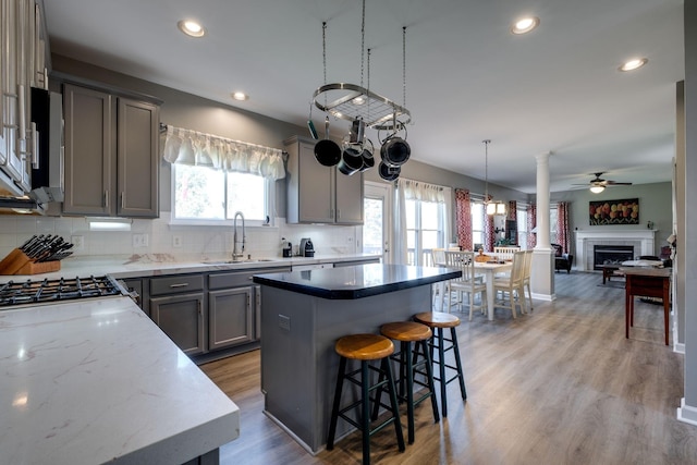 kitchen featuring a sink, light wood finished floors, gray cabinets, a center island, and tasteful backsplash