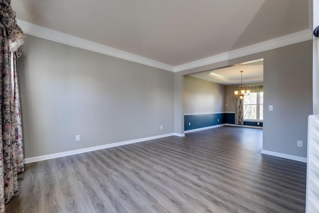 unfurnished living room featuring baseboards, ornamental molding, a notable chandelier, and wood finished floors