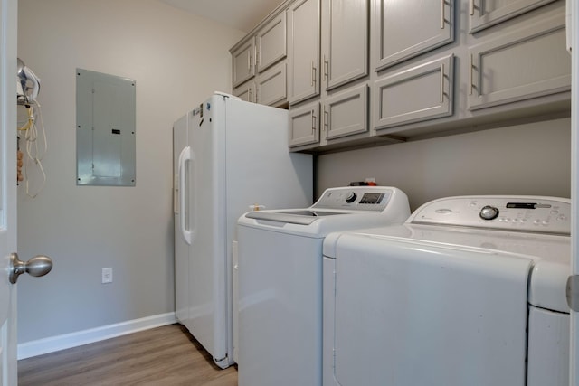 laundry area with light wood-style floors, baseboards, cabinet space, electric panel, and washing machine and clothes dryer