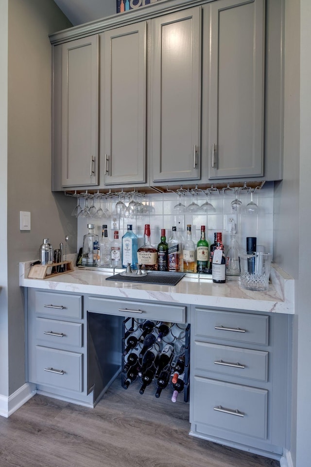 bar with baseboards, indoor bar, decorative backsplash, and wood finished floors