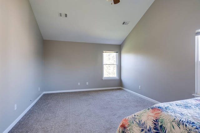 unfurnished bedroom with vaulted ceiling, carpet flooring, visible vents, and baseboards