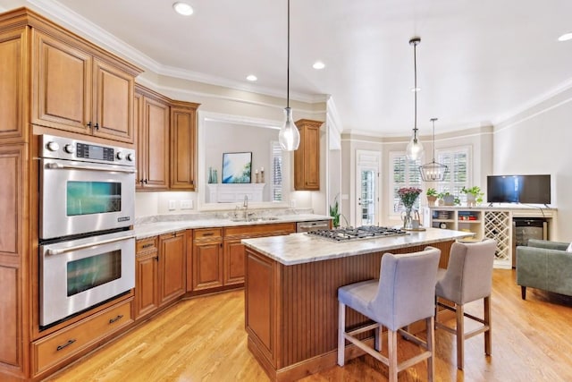 kitchen featuring appliances with stainless steel finishes, open floor plan, a sink, a kitchen island, and a kitchen bar