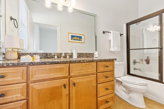 bathroom featuring toilet, vanity, combined bath / shower with glass door, and tile patterned floors