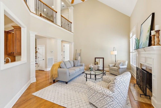 living room with light wood-style floors, decorative columns, a fireplace, and visible vents