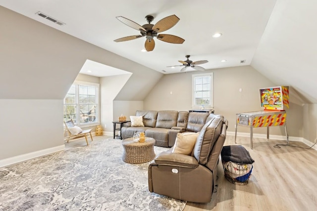 living area with a healthy amount of sunlight, baseboards, visible vents, and wood finished floors