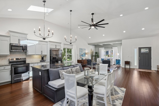 dining room featuring high vaulted ceiling, dark wood-style flooring, a skylight, and recessed lighting