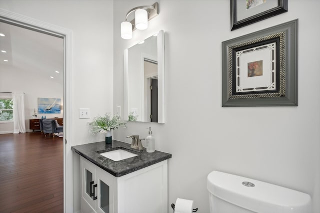 half bathroom with toilet, wood finished floors, and vanity