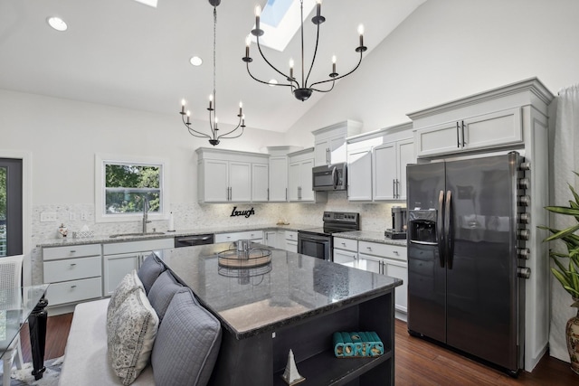 kitchen featuring decorative backsplash, dark wood finished floors, appliances with stainless steel finishes, stone counters, and a sink