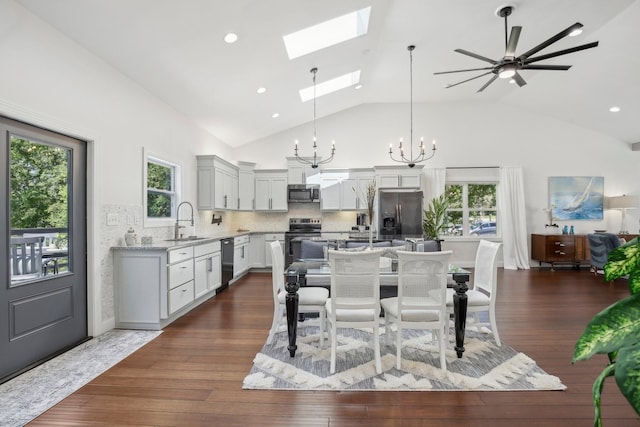 dining room featuring dark wood-style floors, a skylight, a wealth of natural light, and an inviting chandelier