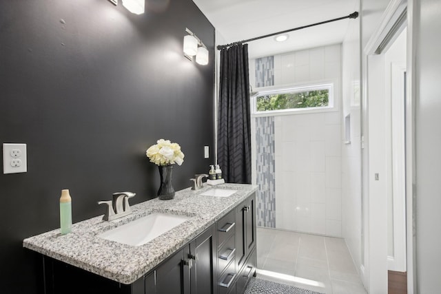 full bathroom with double vanity, a tile shower, a sink, and tile patterned floors