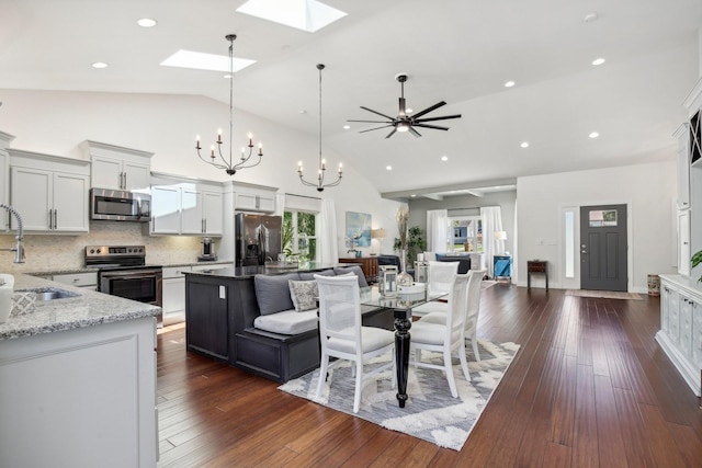 kitchen with stainless steel appliances, dark wood-type flooring, a sink, open floor plan, and a center island with sink