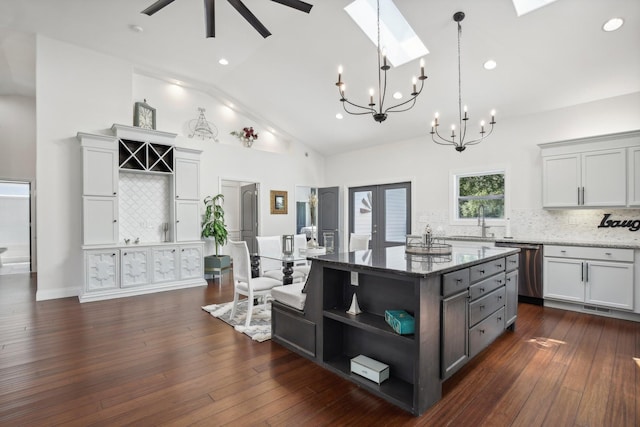 kitchen with dark wood-type flooring, a skylight, a sink, dishwasher, and open shelves