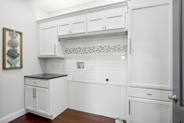 laundry area with dark wood-type flooring, hookup for a washing machine, cabinet space, and baseboards