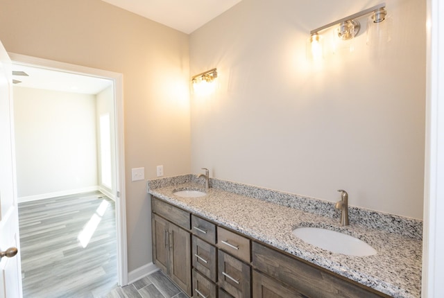 bathroom featuring double vanity, baseboards, a sink, and wood finished floors