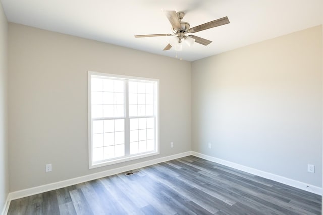 empty room featuring visible vents, dark wood finished floors, and baseboards