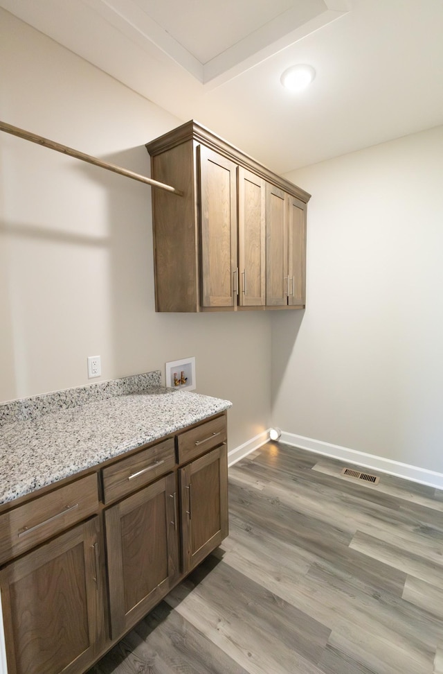 washroom featuring hookup for a washing machine, wood finished floors, visible vents, baseboards, and cabinet space