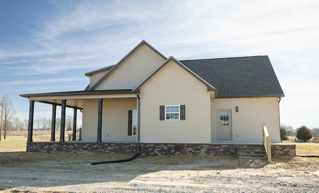 view of front of property with a shingled roof and brick siding