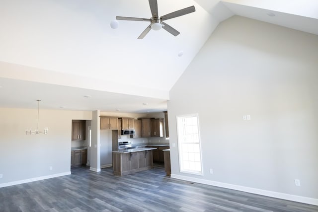 kitchen with dark wood finished floors, appliances with stainless steel finishes, open floor plan, a kitchen island, and high vaulted ceiling