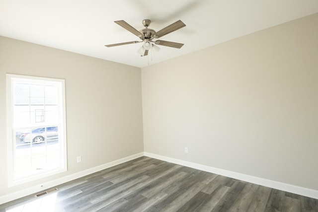 spare room featuring ceiling fan, dark wood finished floors, visible vents, and baseboards