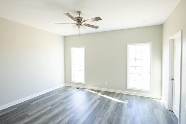 spare room with a healthy amount of sunlight, a ceiling fan, baseboards, and dark wood-style flooring