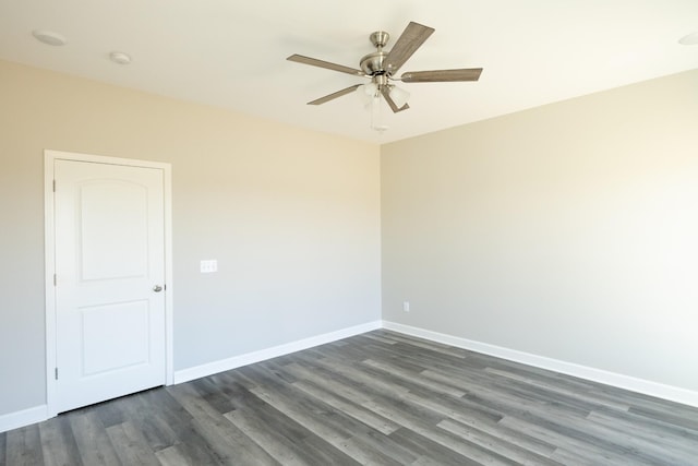 empty room featuring dark wood finished floors, a ceiling fan, and baseboards