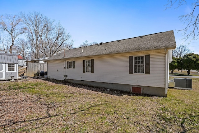 back of property with a shingled roof, crawl space, cooling unit, and a lawn