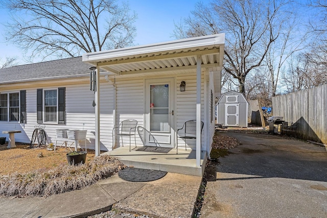 view of front of property featuring an outbuilding, a storage unit, a porch, and fence