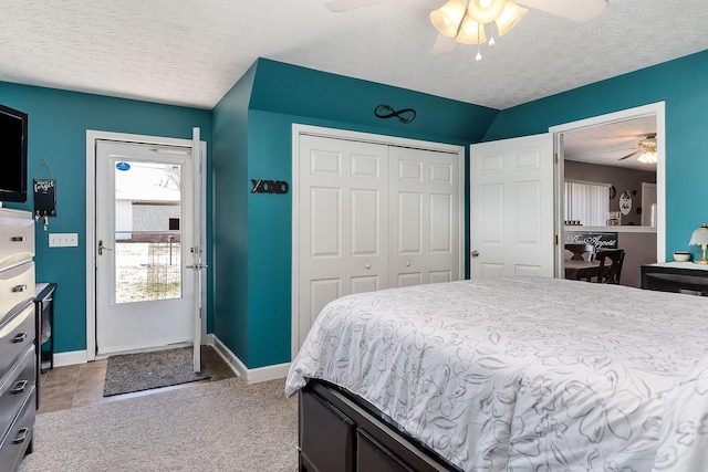 carpeted bedroom with a closet, ceiling fan, a textured ceiling, and baseboards