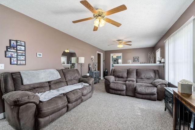 carpeted living room with arched walkways, vaulted ceiling, and a textured ceiling