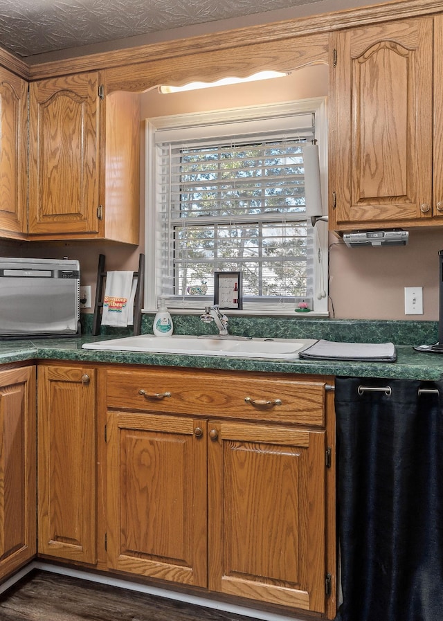 kitchen with dark countertops, brown cabinetry, and a sink