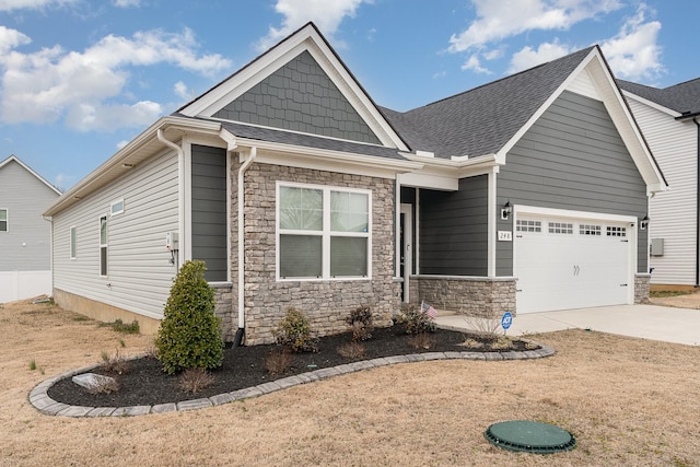 craftsman-style home with a garage, stone siding, driveway, and roof with shingles