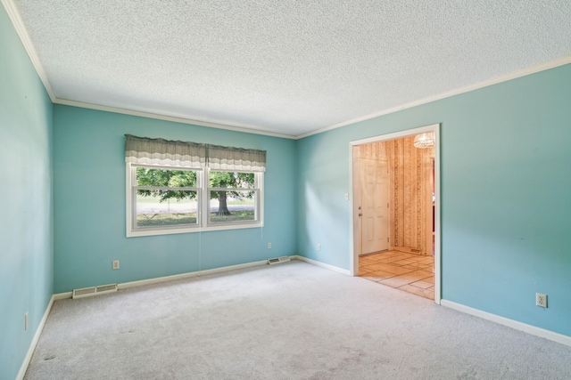 spare room with carpet, a textured ceiling, visible vents, and crown molding