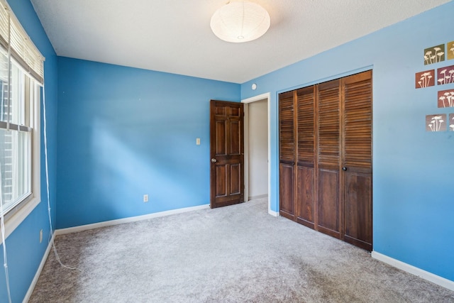 unfurnished bedroom with carpet floors, a closet, and baseboards