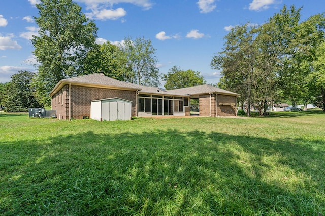 rear view of house with a storage shed, a yard, brick siding, and a sunroom