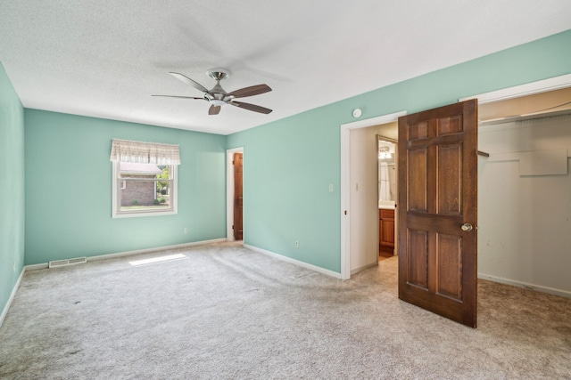 unfurnished bedroom with light carpet, baseboards, visible vents, a walk in closet, and a closet