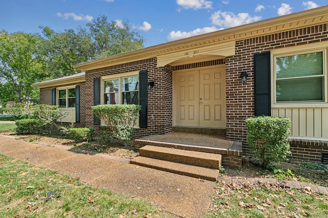 property entrance with board and batten siding and brick siding