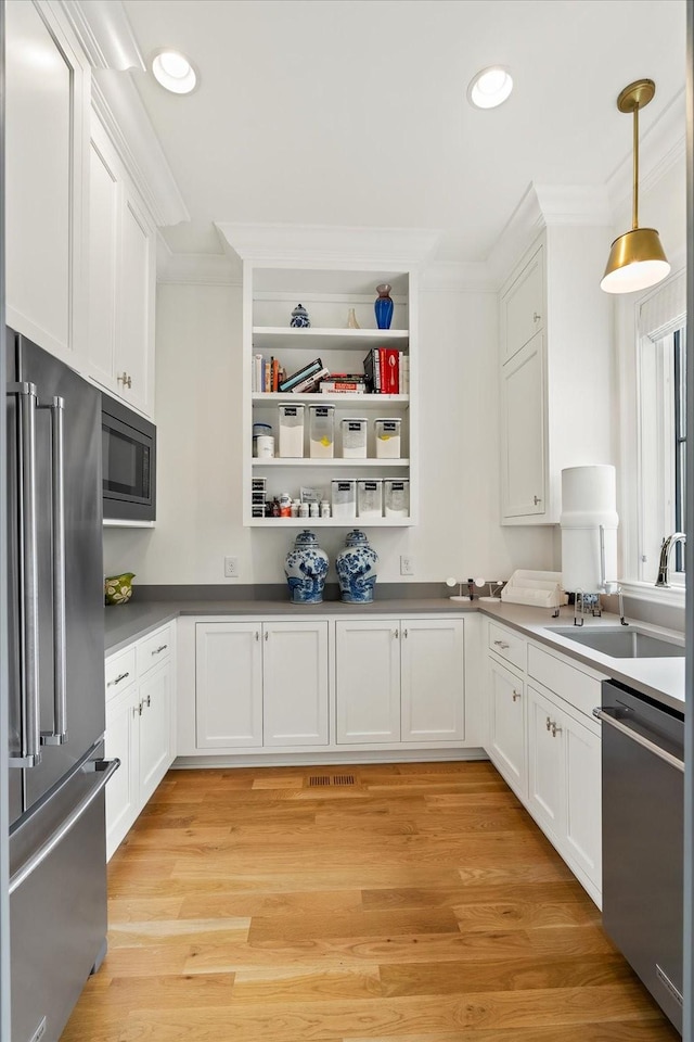 kitchen with stainless steel appliances, white cabinets, a sink, and crown molding