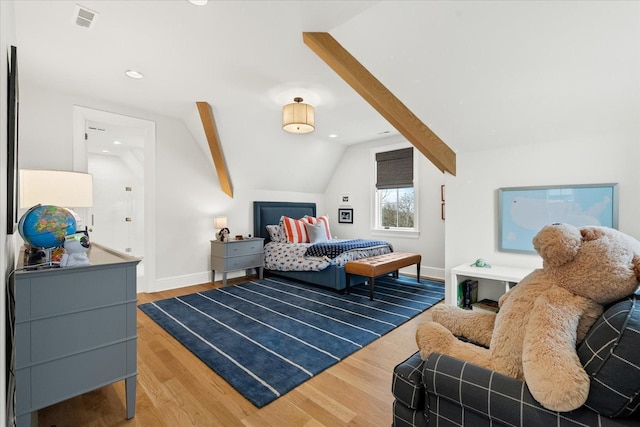 bedroom with lofted ceiling, wood finished floors, visible vents, and baseboards