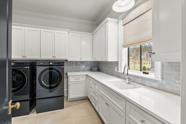 laundry room featuring crown molding, cabinet space, light tile patterned flooring, a sink, and independent washer and dryer