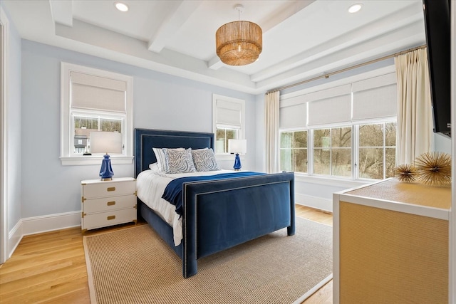 bedroom featuring beam ceiling, multiple windows, and light wood finished floors