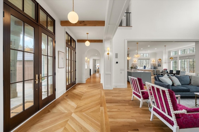 interior space with arched walkways, parquet flooring, beam ceiling, and baseboards