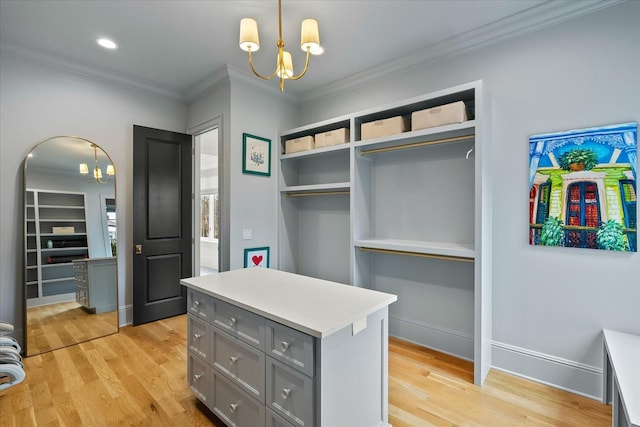 spacious closet featuring an inviting chandelier, light wood-style flooring, and arched walkways